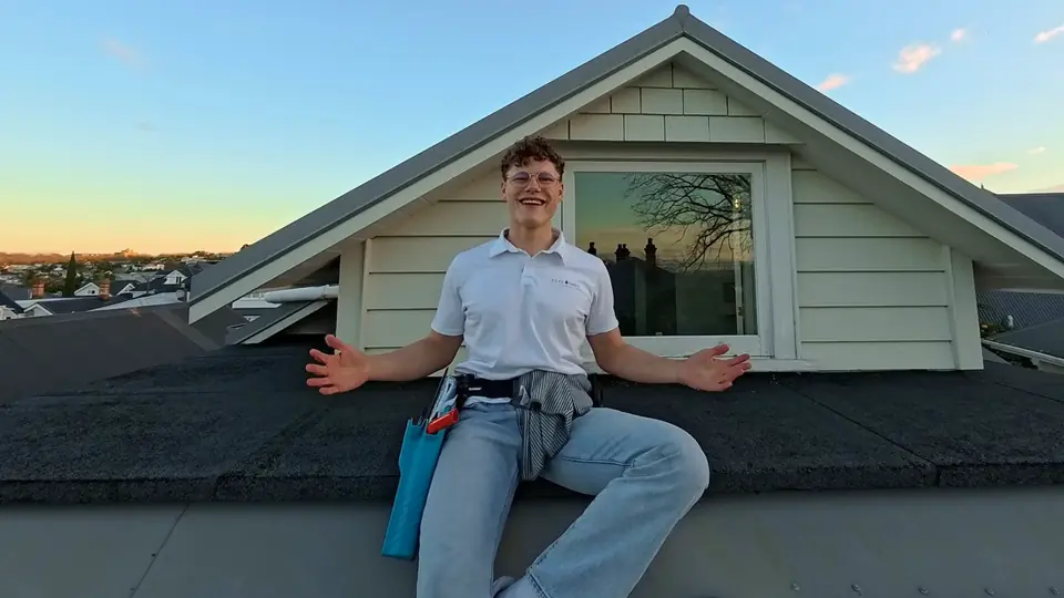Kilian from Feelgood Cleaning sitting on a roof in Auckland at sunset